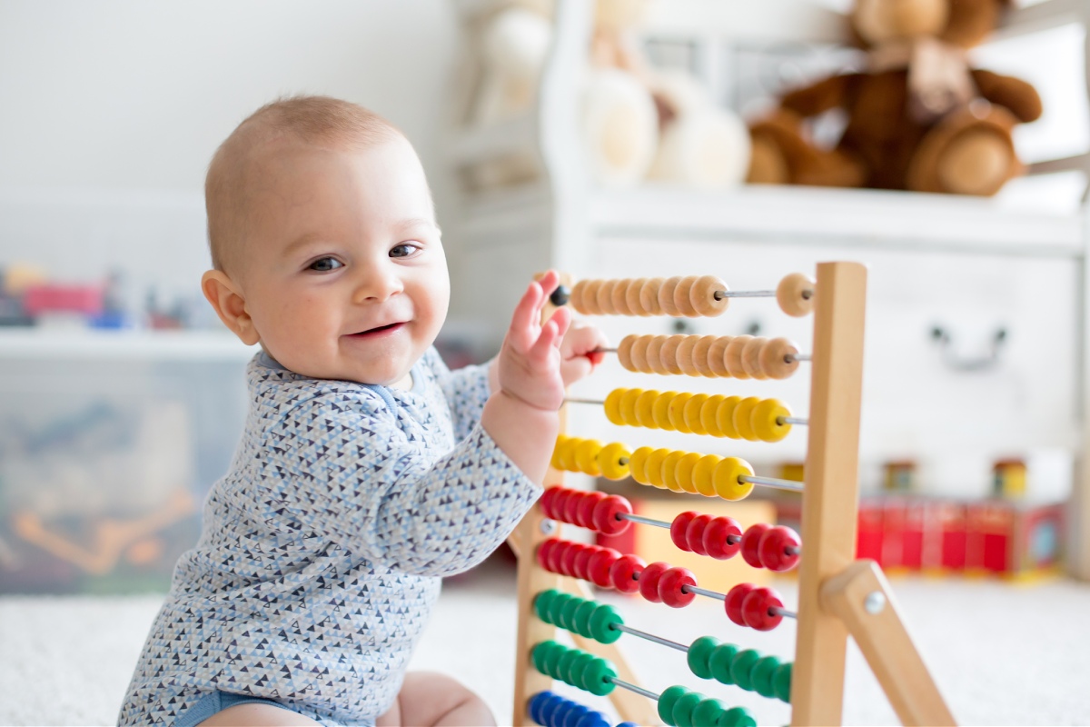 baby sitting on floor and playing with an abacus