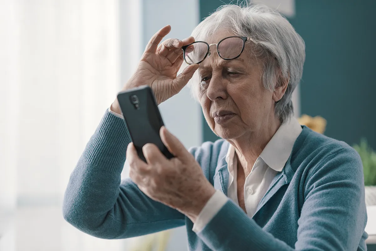 an older woman looking at her phone and having trouble seeing it